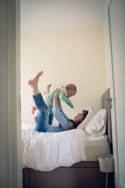 Mother playing with her baby girl in bedroom at home — Stock Photo