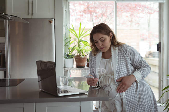 Mulher grávida usando telefone celular em casa — Fotografia de Stock