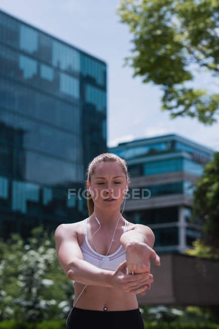 Giovane donna sportiva che si estende sulla strada — Foto stock