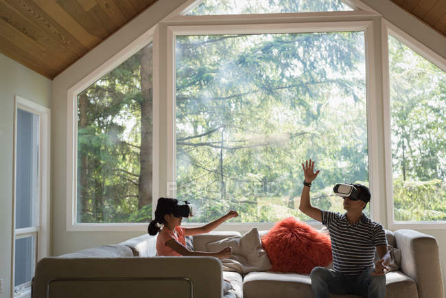 Отец и дочь используют гарнитуру виртуальной реальности в гостиной дома — стоковое фото