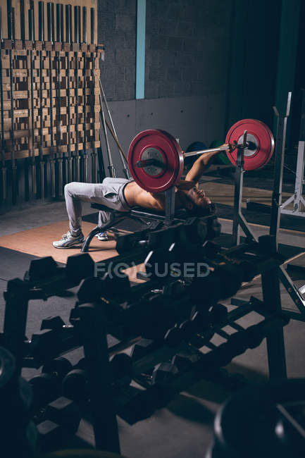 М'язистий чоловік займається з барбелом у фітнес-студії — стокове фото