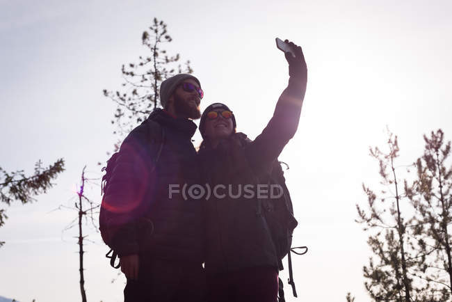 Coppia escursionista scattare selfie con il telefono cellulare in una giornata di sole — Foto stock