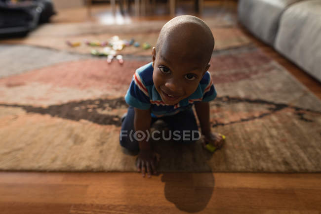 Porträt eines Jungen, der es sich auf Teppich im heimischen Wohnzimmer gemütlich macht. — Stockfoto