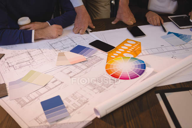 Business people discussing blueprints and graph chart in office. — Stock Photo