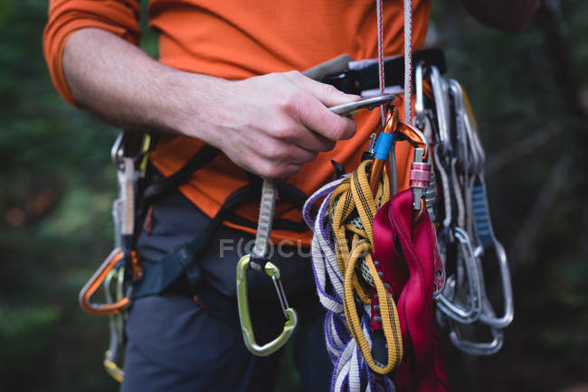 Mid section of hiker adjusting the carabiner on rope — Stock Photo