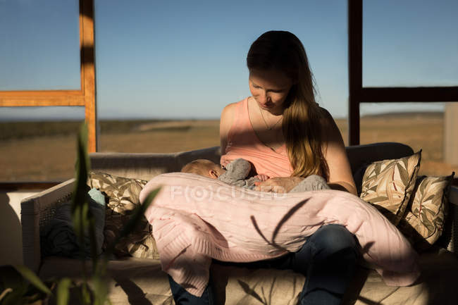 Mother breastfeeding baby boy in sunlight outdoors. — Stock Photo