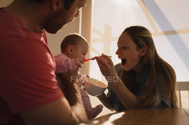 Happy parents feeding baby son at home. — Stock Photo