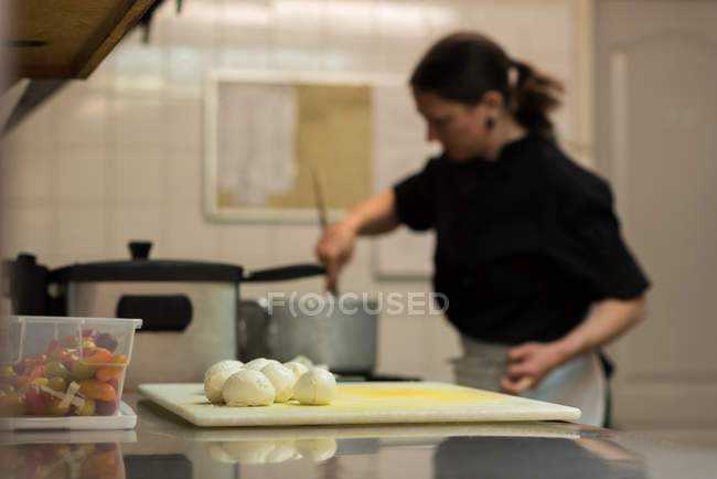 Balls of dough on a chopping board while chef cooking in background — Stock Photo