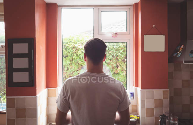 Vue arrière de l'homme debout dans l'intérieur de la cuisine . — Photo de stock
