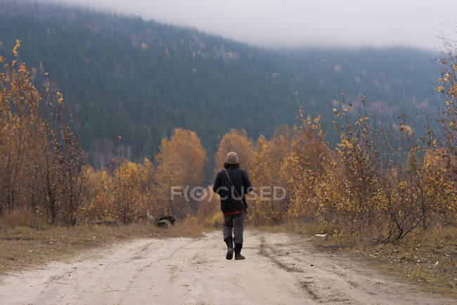 Man walking on empty path surrounded with bushes — Stock Photo