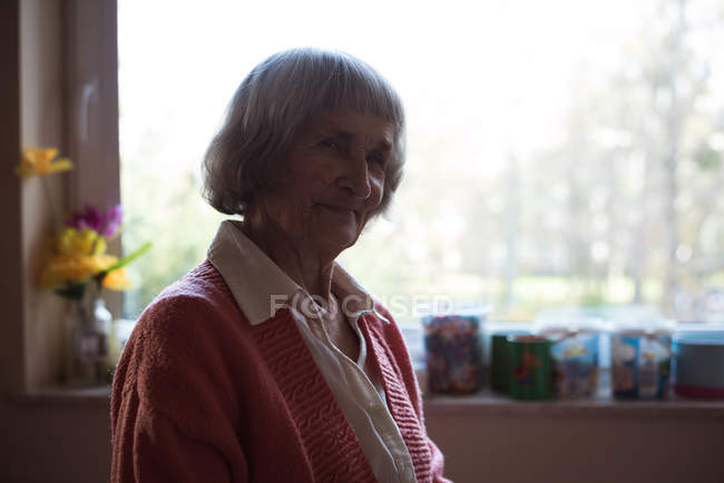 Улыбающаяся пожилая женщина сидит в доме престарелых — стоковое фото