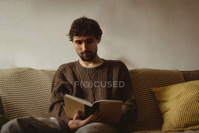 Человек читает книгу в гостиной дома — стоковое фото