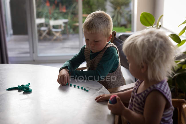 Geschwister spielen im heimischen Wohnzimmer mit Ton. — Stockfoto