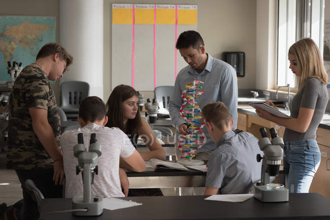 Teacher assisting students in experiment on molecule in laboratory — Stock Photo