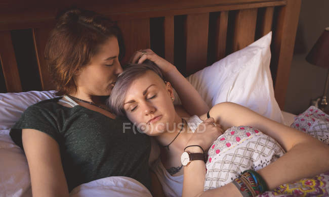 Pareja lesbiana abrazándose en la cama en el dormitorio en casa . - foto de stock