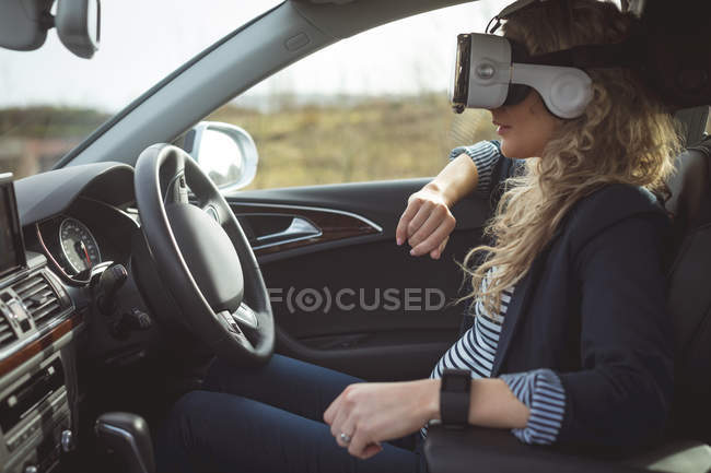 Visão lateral do executivo feminino usando fone de ouvido de realidade virtual em um carro — Fotografia de Stock