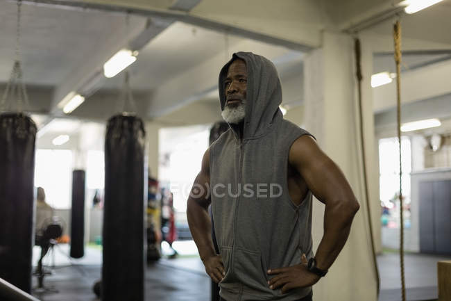 Déterminé homme âgé en sweat à capuche debout dans un studio de fitness . — Photo de stock