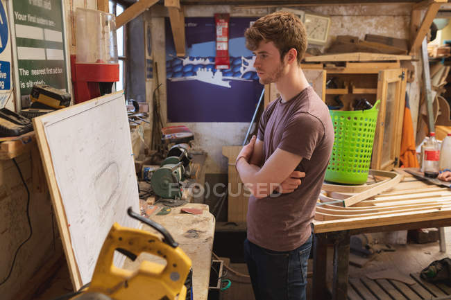 Carpintero masculino mirando la carta en el taller - foto de stock
