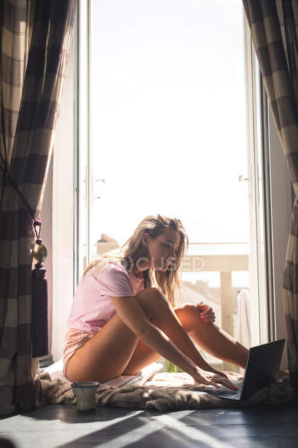 Женщина с ноутбуком рядом с дверью балкона дома . — стоковое фото