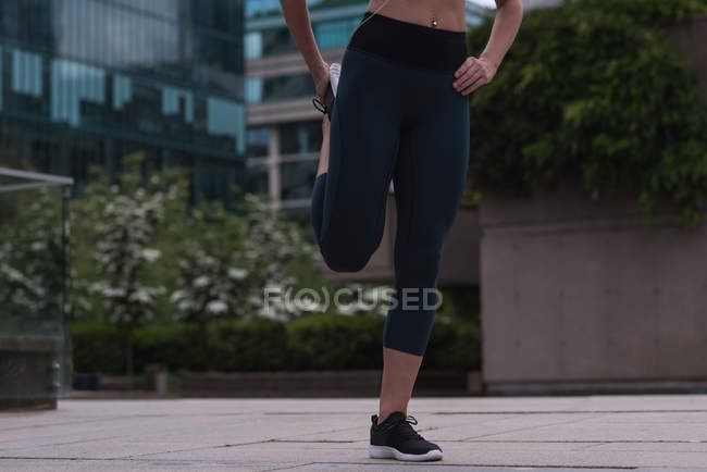 Low section of sporty woman stretching on street — Stock Photo