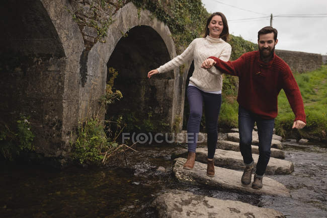 Pareja feliz corriendo por el camino de piedra en el río - foto de stock