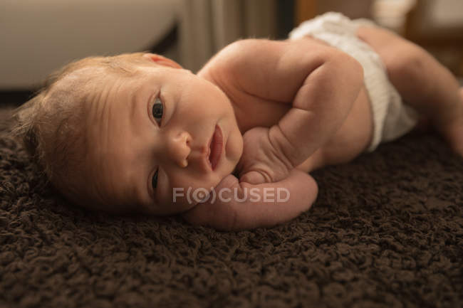 Recém-nascido bebê relaxante em cobertor marrom em casa . — Fotografia de Stock