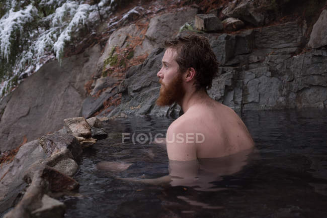 Thoughtful man relaxing in hot spring during winter — Stock Photo