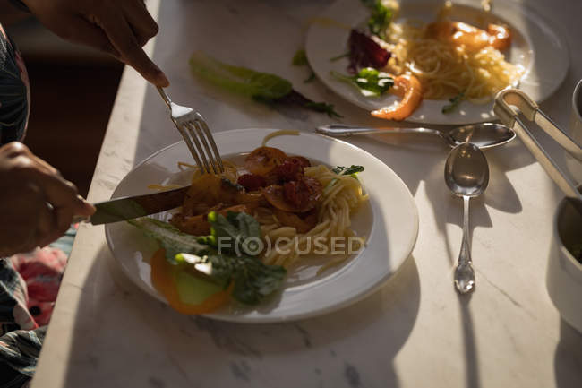 Primer plano de las manos femeninas que tienen pasta con verduras en la mesa de casa . - foto de stock
