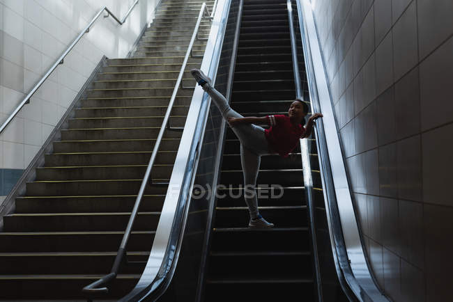 Mulher dançarina de rua dançando na escada rolante na estação ferroviária — Fotografia de Stock