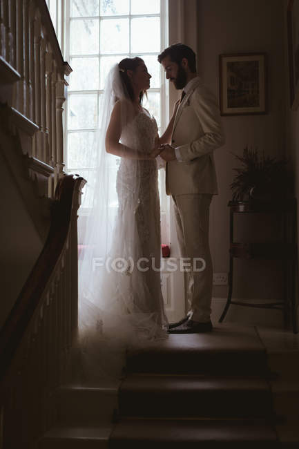 Braut und Bräutigam halten Händchen auf den Stufen zu Hause — Stockfoto