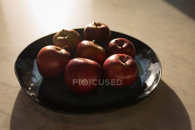 Яблука на керамічному лотку за кухонним столом . — стокове фото