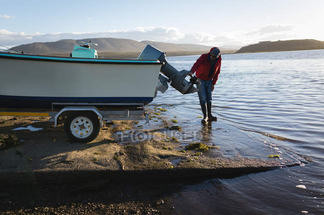 Uomo che controlla barca a motore vicino al fiume
. — Foto stock