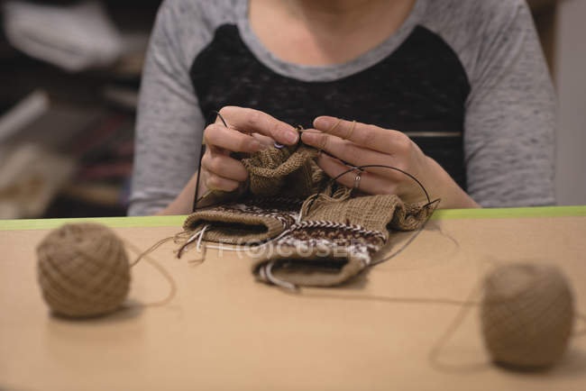 Sección media de la mujer tejiendo lana en sastrería - foto de stock