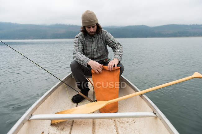 Mann im Boot öffnet seine orangefarbene Tasche — Stockfoto