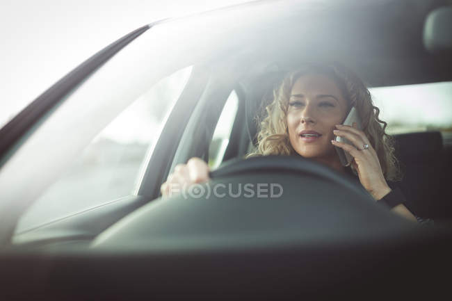 Gros plan d'une femme exécutive parlant sur un téléphone portable alors qu'elle conduisait une voiture — Photo de stock
