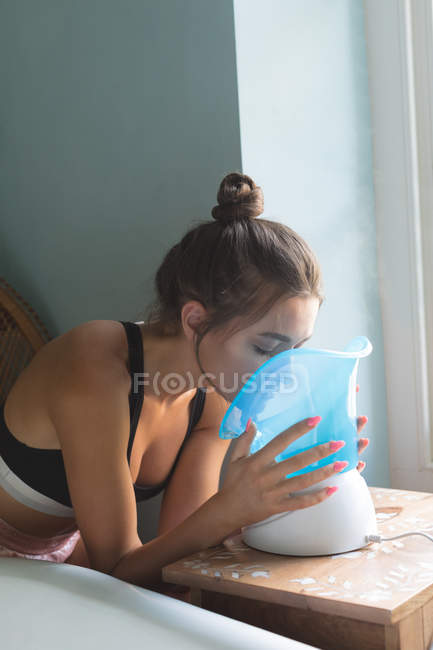 Donna che utilizza sauna facciale blu a casa . — Foto stock