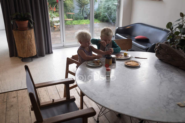 Crianças tomando café da manhã na sala de estar em casa . — Fotografia de Stock