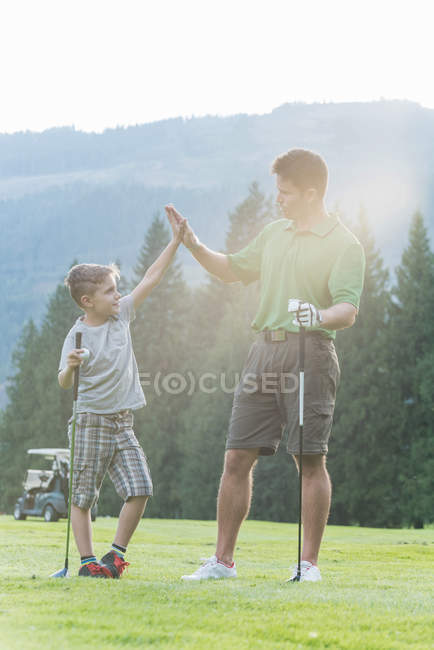 Padre e hijo dando choca los cinco entre sí en el curso - foto de stock