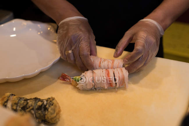 Koch bereitet Sushi auf Schneidebrett in der Küche zu — Stockfoto