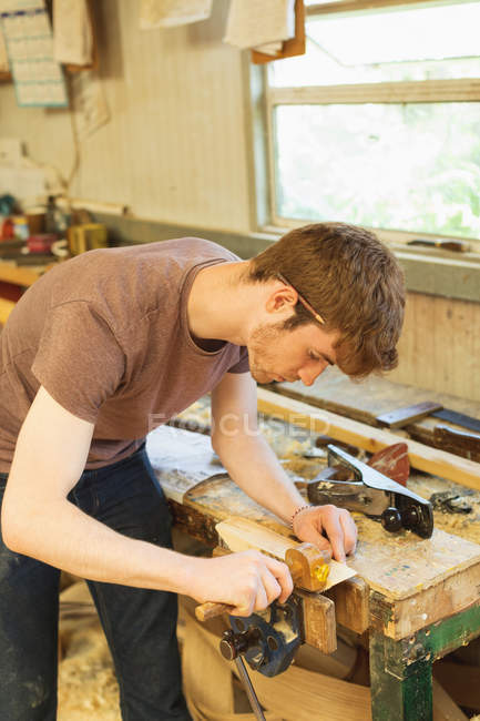 Joven carpintero masculino utilizando el indicador de marcado en el taller - foto de stock