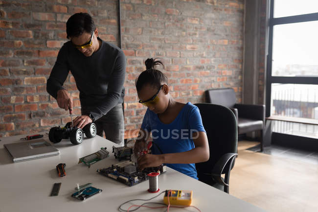 Father and daughter repairing electric model car and circuit board in office. — Stock Photo