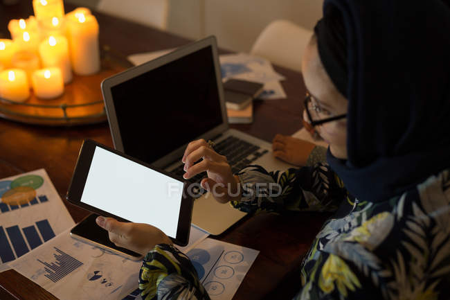 Mujer musulmana usando tableta digital y portátil en casa — Stock Photo