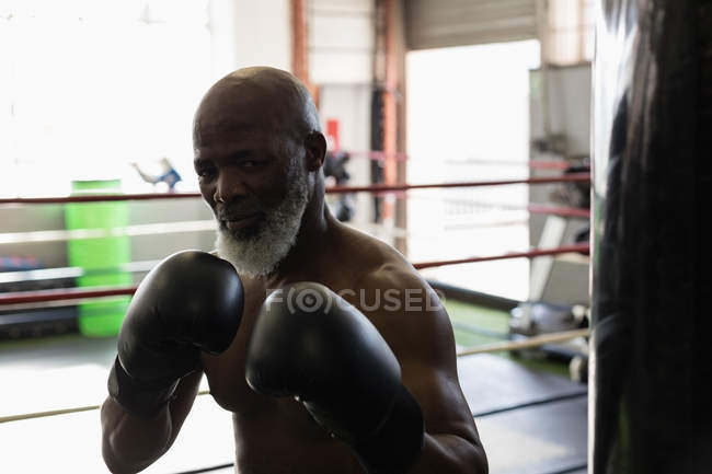 Determined senior man boxing in boxing ring. — Stock Photo