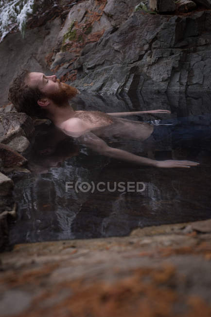 Handsome man relaxing in hot spring during winter — Stock Photo