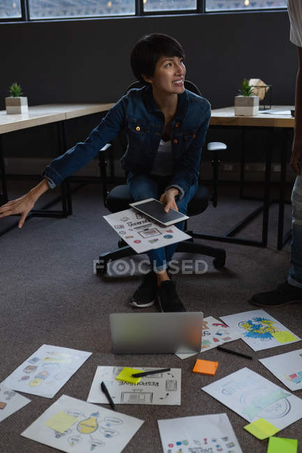 Businesswoman with digital tablet and laptop discussing over documents in office. — Stock Photo