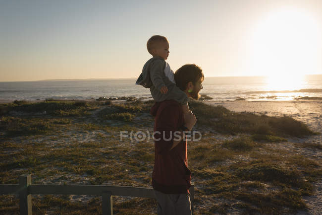 Padre e hijo divirtiéndose en la playa al atardecer - foto de stock