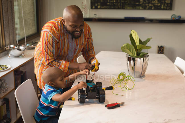Отец и сын ремонтируют электромобиль за домашним столом . — стоковое фото