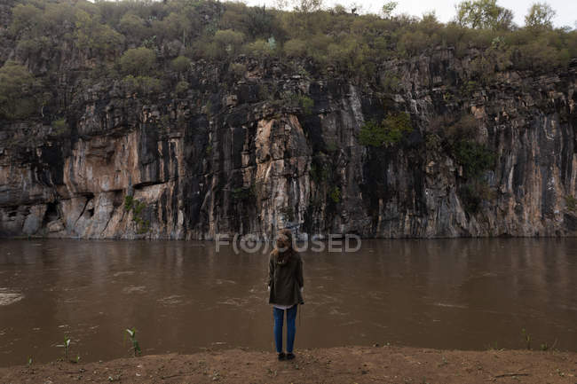 Вид сзади на женщину, стоящую возле реки в солнечный день — стоковое фото