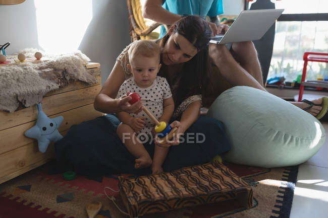 Mother and daughter playing with toy in living room at home — Stock Photo