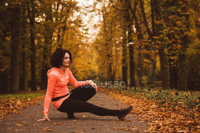 Woman performing stretching exercise in forest during autum season — Stock Photo